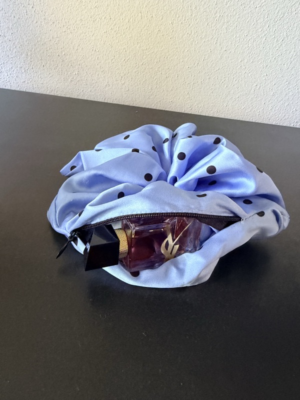 The light blue scrunchie with its zip open and a perfume bottle inside
